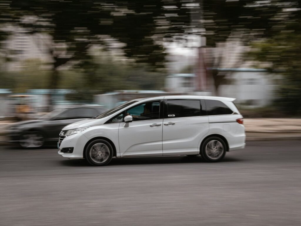 a white van driving down a street next to a forest